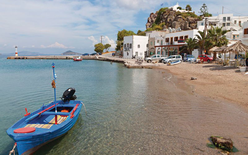 Panos Karapanagiotis ein Bild von Panos Karapanagiotis auf Patmos mit Blick auf den Strand, das Meer, ein Boot und Gebäude