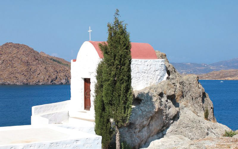 Patmos ein Bild von Patmos mit Blick auf ein kleines Gebäude, einen Baum und das Meer im Hintergrund