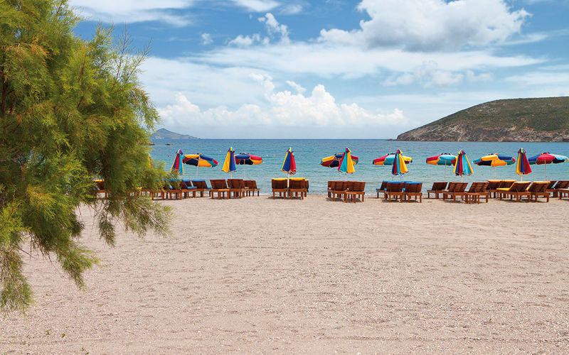 Panos Karapanagiotis ein Bild von Panos Karapanagiotis auf Patmos mit Blick auf den Strand, Sonnenschirme, Liegestühle und das Meer